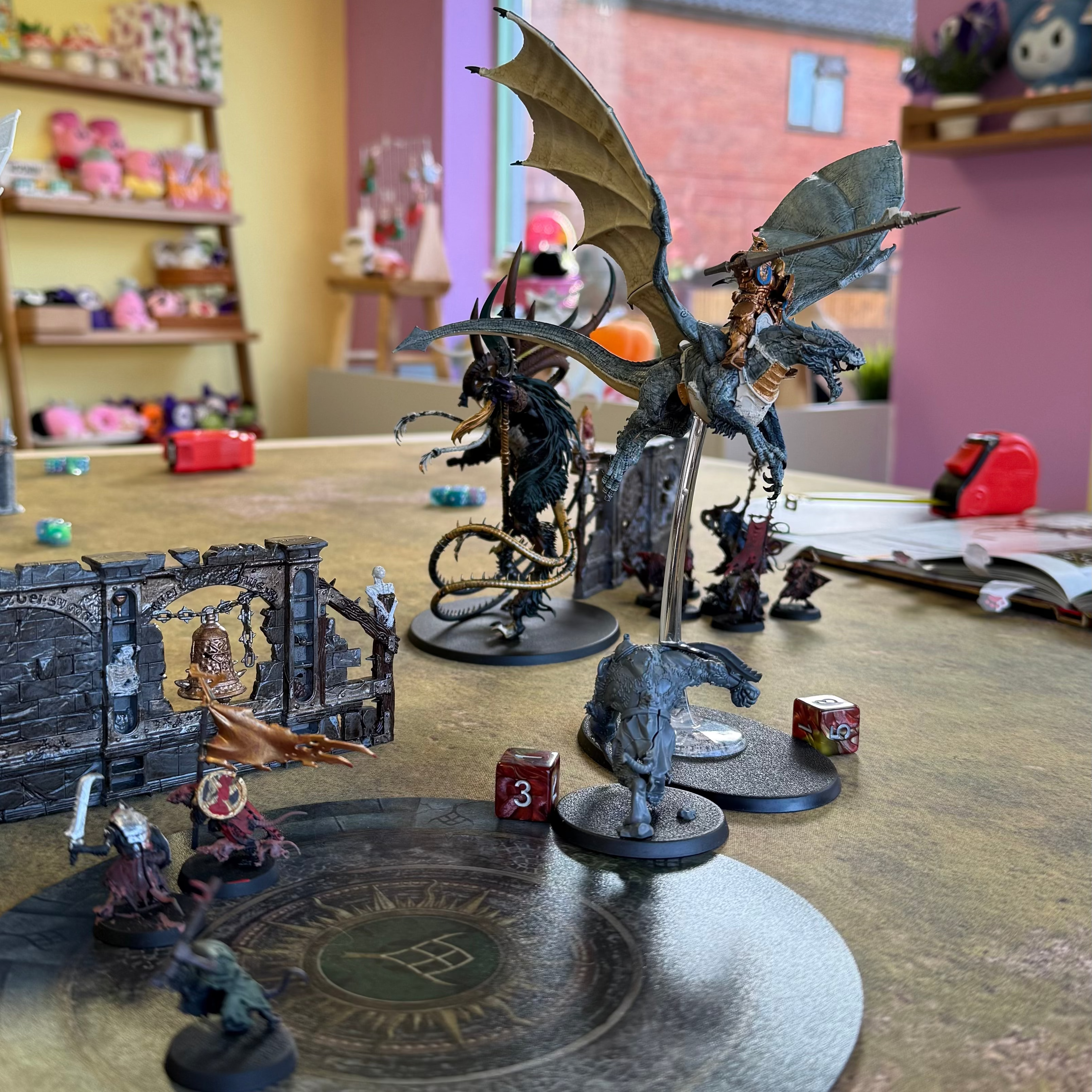 Tabletop wargame setup with fantasy figurines and dice on a wooden surface.